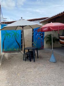 a table and chair under an umbrella next to a building at Pousada da vila in Beberibe