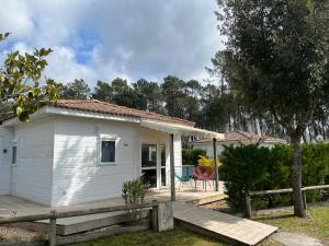 a white tiny house with a wooden deck at Chalet en Parc résidentiel pour 4 personnes à proximité de la plage in Lit-et-Mixe