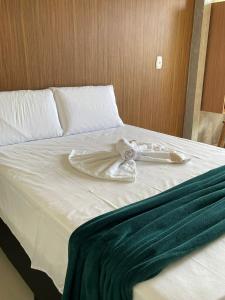 a white bed with a green blanket on it at Pousada da Samira in Andaraí