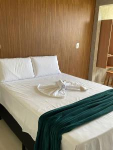 a white bed with a green towel on it at Pousada da Samira in Andaraí