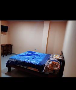 a bed with a blue comforter in a room at Hostal Iruña in Loja