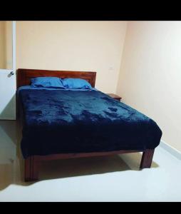 a bedroom with a bed with a blue comforter at Hostal Iruña in Loja