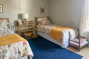 a bedroom with two beds and a blue rug at Forest Views, Deck and Fireplace Fort Valley Escape in Carmel