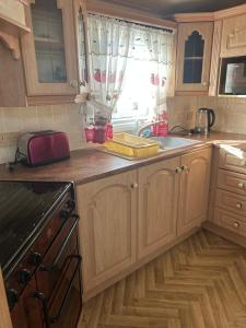 a kitchen with wooden cabinets and a window at 6 berth caravan ensuite the chase in Ingoldmells