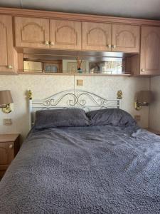 a bed in a bedroom with wooden cabinets at 6 berth caravan ensuite the chase in Ingoldmells