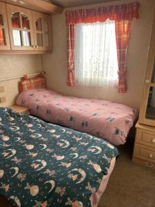 a bedroom with two beds and a window at 6 berth caravan ensuite the chase in Ingoldmells