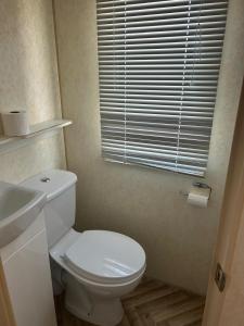 a bathroom with a toilet and a sink and a window at 6 berth caravan ensuite the chase in Ingoldmells