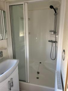 a white bathroom with a shower and a sink at 6 berth caravan ensuite the chase in Ingoldmells