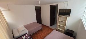 a small room with a bed and a flat screen tv at Tierra Mágica Hostal in Machu Picchu +22 photos