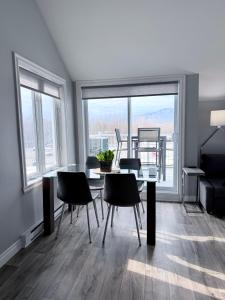 a dining room with a table and chairs and a large window at La Première vue in Magog-Orford