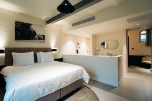 a bedroom with a large white bed and a bathroom at Hotel Colonie 7 in Merksplas