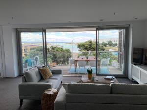a living room with a couch and a large glass window at The Bay Riveria in Napier