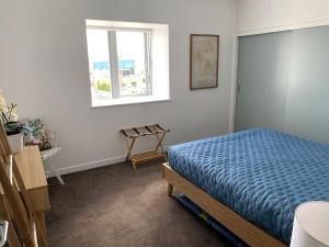 a bedroom with a blue bed and a window at The Bay Riveria in Napier