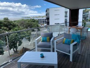 a balcony with two chairs and a table on a balcony at The Bay Riveria in Napier +6 photos
