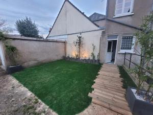 a small backyard with a lawn and a house at appartement proche gare SNCF in Tours