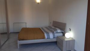 a bedroom with a bed and a night stand with a lamp at Casa Vacanza Pineta in Oltrona di San Mamette