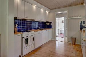 a kitchen with white appliances and a wooden floor at Peaceful Getaway in Åsljunga