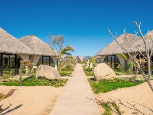 a pathway through a village with thatched roofs at Mayto Astrological Park in Maito