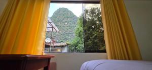 a bedroom with a view of a mountain from a window at Tierra Mágica Hostal in Machu Picchu