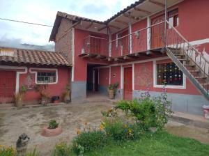 a red house with a staircase and a balcony at Hospedaje Q'ello Qantu in Coper
