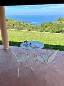 a table and chairs on a patio with a view of the ocean at BLUE APARTMENT in VILLA ANGISI in Drapia