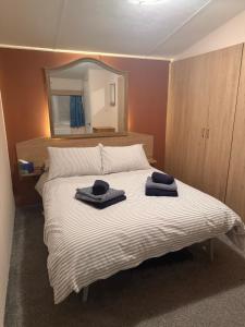 a bedroom with a bed with two towels on it at Coastal Beachfront Caravan in Brightlingsea +27 photos
