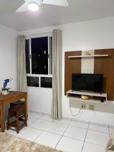 a living room with a television and a table and a window at Apartamento enseada in Guarujá