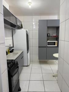 a white kitchen with a refrigerator and a sink at Apartamento enseada in Guarujá