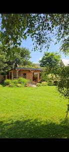 a house in a field with a green yard at Sjesta al mare, domki z sauną i balią z jacuzzi in Lubiatowo
