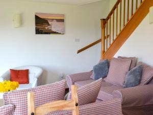 a living room with two chairs and a staircase at Keel Cottage in Whitby
