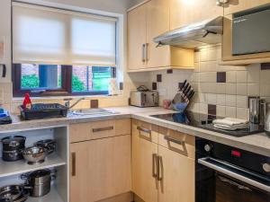 a kitchen with wooden cabinets and a sink and a window at Keel Cottage in Whitby