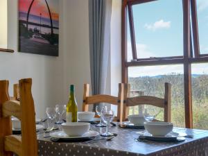 a dining table with a bottle of wine and a window at Keel Cottage in Whitby