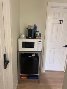 a microwave on a stand in a room with a door at Maple & Moon in Richmond