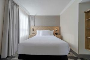 a bedroom with a white bed and a window at Sandman Signature Mississauga Hotel in Mississauga