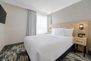 a hotel room with a large bed and a window at Sandman Signature Mississauga Hotel in Mississauga