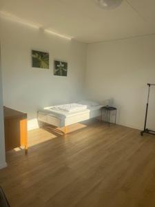 a white room with a bed and a wooden floor at Havfruens Lejlighed in Rødby