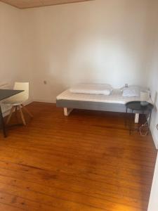 a bed in a room with a wooden floor at Havfruens Lejlighed in Rødby