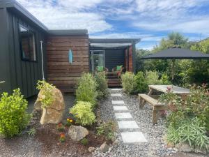 a garden with a cabin with a table and an umbrella at Beach Bach Whangaumu Bay Tutukaka in Tutukaka