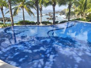 a large swimming pool next to the ocean with palm trees at Oceanfront Designer Penthouse, Private Pool in Ixtapa +27 photos