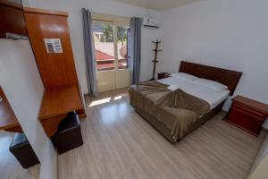 a bedroom with a bed and a large window at Pousada Prime Gramado in Gramado