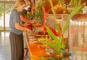 a woman standing in front of a buffet line with food at Hacienda Herrera Tambopata in Puerto Maldonado +75 photos