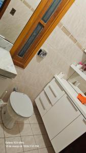 ein Badezimmer mit weißer Toilette und Waschbecken in der Unterkunft Mimi Nova in Osório