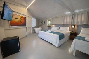 a bedroom with a bed and a flat screen tv at Pousada Estalagem do Porto in Arraial do Cabo +87 photos