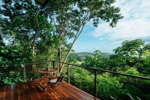 a wooden deck with a table and a chair on it at Stylish Tiny Home with Sea View and Bathtub in Alto del Espino Prieto