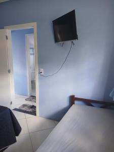 a bedroom with a bed with a flat screen tv on the wall at Casa Azul Marichi Hospedagem in Vale do Capao