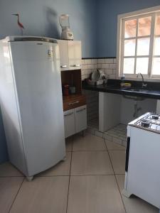 a kitchen with a white refrigerator and a sink at Casa Azul Marichi Hospedagem in Vale do Capao