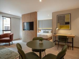 a hotel room with a bed and a table and chairs at Bomma House - Parque 93 in Bogotá