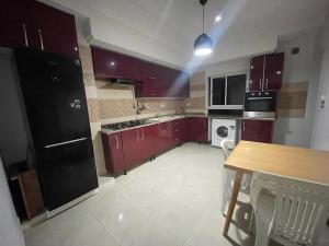 a kitchen with red cabinets and a wooden table at Hsan Bouslimi in Ez Zahra