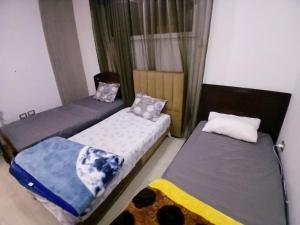 two twin beds in a room with a window at Hsan Bouslimi in Ez Zahra