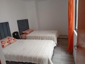 two beds in a room with white sheets at HOTEL CHOQOLAqA RESTAURANT in Cabanaconde